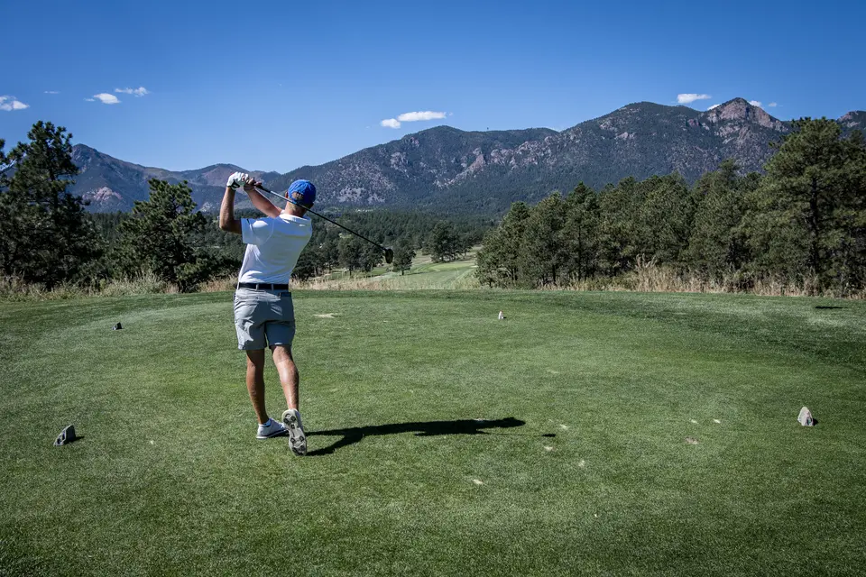 A golfer driving the ball down a fairway at the Eisenhower Golf Course